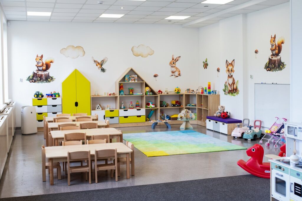 Żłobek w Będzinie – Zaczarowany Las. Sala dla dzieci z zabawkami, stolikami i bajkowymi dekoracjami na ścianach.