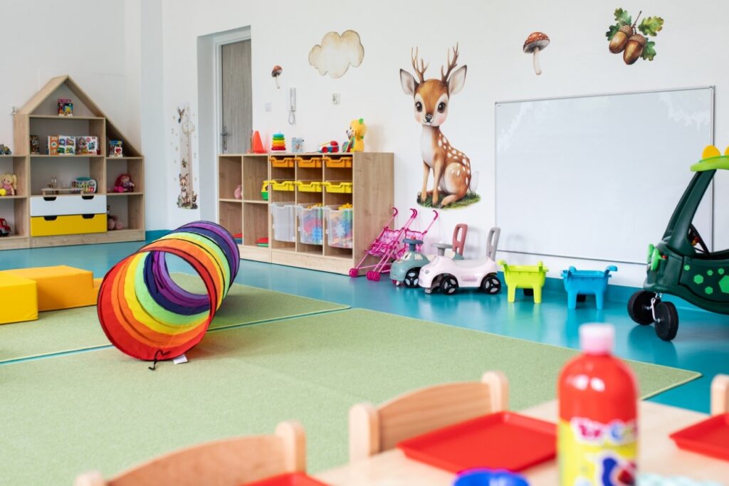 Sala zabaw w żłobku w Będzinie - Zaczarowany Las. Przestrzeń z jeździkami, tunelem, regałami i przyjaznymi dekoracjami.
