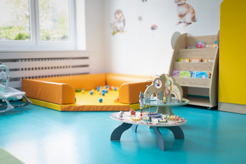 Żłobek w Będzinie Zaczarowany Las - kącik dla najmłodszych z basenem z piłeczkami, stolikami sensorycznymi i półką z książkami dla dzieci.