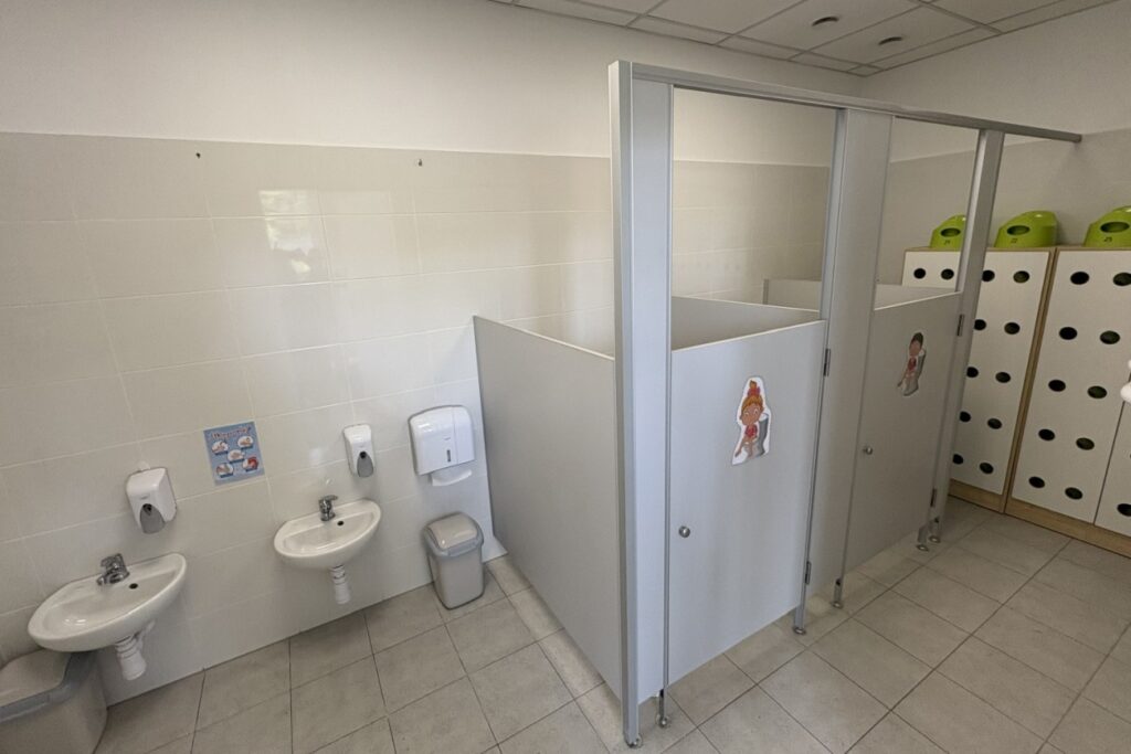 Toaleta w żłobku Zaczarowany Las w Będzinie - przestrzeń wspierająca samodzielność dzieci, z kabinami i instrukcją mycia rąk.